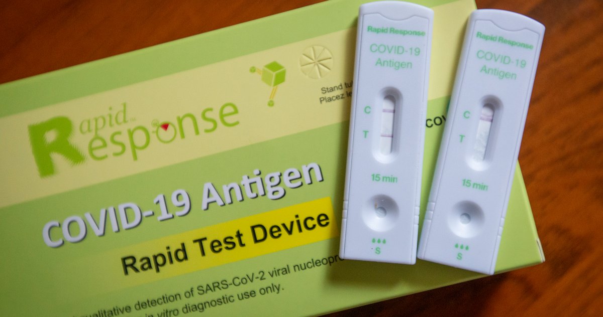 Photo of two white COVID-19 rapid tests, and a green box with the text Rapid Response COVID-19 Antigen Rapid Test Device