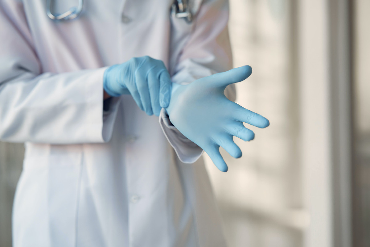 Photo of a healthcare worker who is wearing blue sterile gloves. Photo by Gustavo Fring via Pexels.